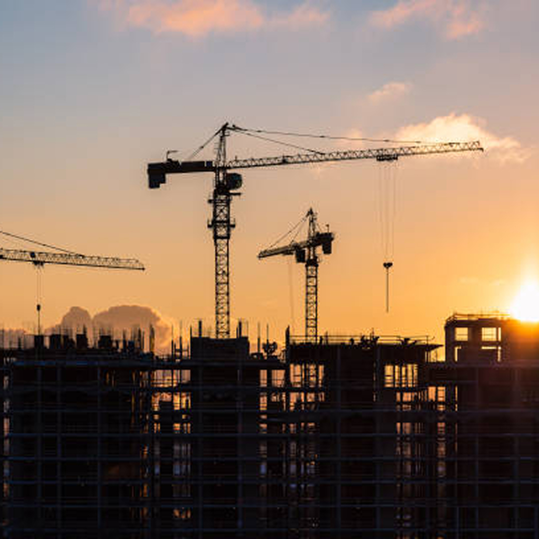 Construction cranes at sunset